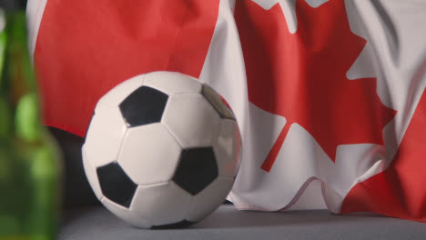 Flagge-Kanadas-Zu-Hause-über-Sofa-Drapiert,-Fußball-Bereit-Für-Spiel-Im-Fernsehen-2