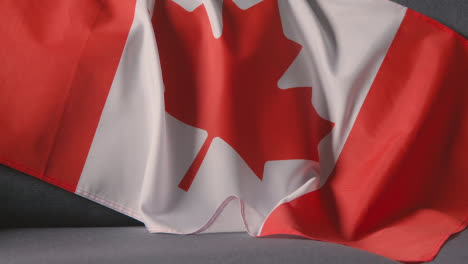 Nahaufnahme-Der-Flagge-Kanadas,-Die-Zu-Hause-über-Dem-Sofa-Drapiert-Ist,-Bereit-Für-Das-Spiel-Im-Fernsehen-1