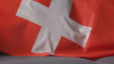 Primer-Plano-De-La-Bandera-De-Suiza-Sobre-Un-Sofá-En-Casa-Listo-Para-El-Partido-En-La-Televisión