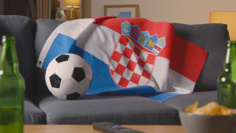 Flagge-Von-Kroatien-Drapiert-über-Dem-Sofa-Zu-Hause-Mit-Fußball-Bereit-Für-Das-Spiel-Im-Fernsehen