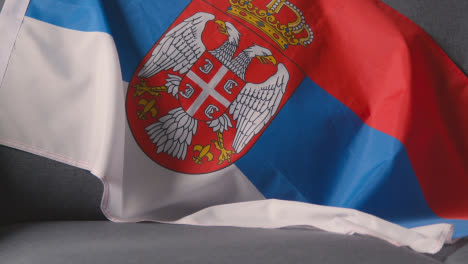 Nahaufnahme-Der-Flagge-Von-Serbien,-Die-Zu-Hause-über-Dem-Sofa-Drapiert-Ist,-Bereit-Für-Das-Spiel-Im-Fernsehen