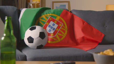 Flagge-Von-Portugal-über-Dem-Sofa-Zu-Hause-Mit-Fußball-Bereit-Für-Das-Spiel-Im-Tv-1