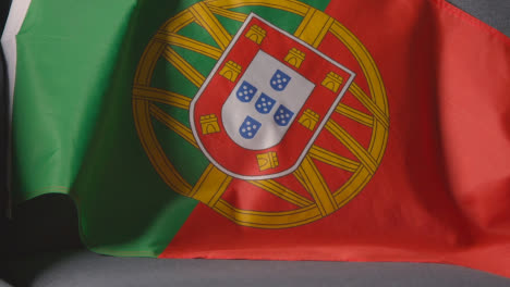 Nahaufnahme-Der-Flagge-Portugals,-Die-Zu-Hause-über-Dem-Sofa-Drapiert-Ist,-Bereit-Für-Das-Spiel-Im-Fernsehen