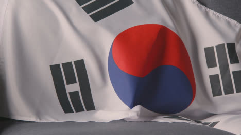 Nahaufnahme-Der-Flagge-Von-Südkorea,-Die-Zu-Hause-über-Dem-Sofa-Drapiert-Ist,-Bereit-Für-Das-Spiel-Im-Fernsehen