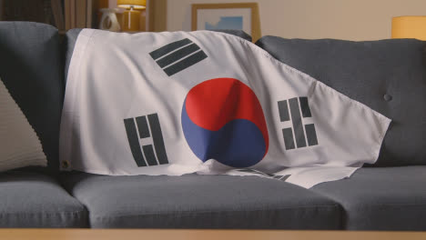 Flagge-Von-Südkorea,-Die-Zu-Hause-über-Dem-Sofa-Drapiert-Ist,-Bereit-Für-Das-Spiel-Im-Fernsehen