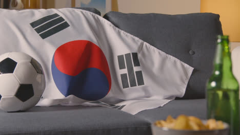 Flagge-Von-Südkorea-Zu-Hause-über-Sofa-Drapiert,-Fußball-Bereit-Für-Spiel-Im-Tv-1