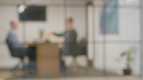 Defocused-Background-Shot-Of-Businesspeople-At-Work-In-Office-Having-Meeting-At-Desk-1