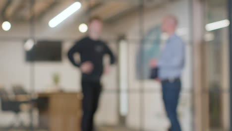 Defocused-Background-Shot-Of-Businesspeople-At-Work-In-Office-Having-Informal-Meeting-