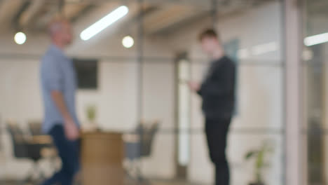 Defokussierter-Hintergrundschuss-Eines-Geschäftsmannes,-Der-Im-Büro-Steht-Und-Telefoniert