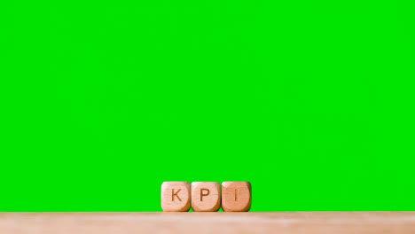 Concepto-De-Negocio-Cubos-De-Letras-De-Madera-O-Dados-De-Ortografía-Kpi-Contra-Pantalla-Verde