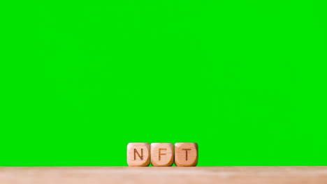 Business-Concept-Wooden-Letter-Cubes-Or-Dice-Spelling-NFT-Against-Green-Screen