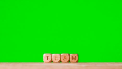 Business-Concept-Wooden-Letter-Cubes-Or-Dice-Spelling-Team-Against-Green-Screen