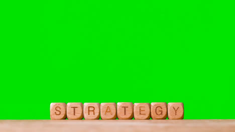 Business-Concept-Wooden-Letter-Cubes-Or-Dice-Spelling-Strategy-Against-Green-Screen
