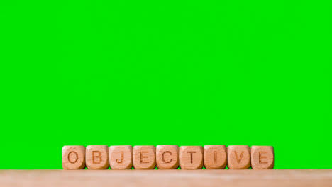 Business-Concept-Wooden-Letter-Cubes-Or-Dice-Spelling-Objective-Against-Green-Screen