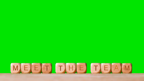 Business-Concept-Wooden-Letter-Cubes-Or-Dice-Spelling-Meet-The-Team-Against-Green-Screen
