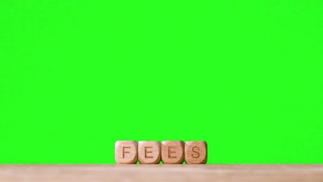 Education-Concept-With-Wooden-Letter-Cubes-Or-Dice-Spelling-Fees-Against-Green-Screen