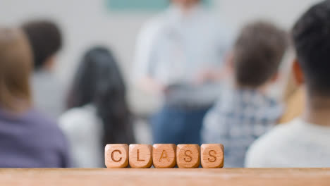 Education-Concept-With-Wooden-Letter-Cubes-Or-Dice-Spelling-Class-With-Student-Lecture-In-Background