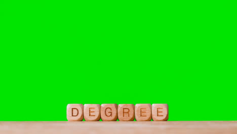 Education-Concept-With-Wooden-Letter-Cubes-Or-Dice-Spelling-Degree-Against-Green-Screen-Background