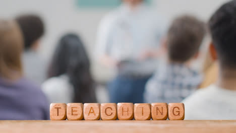 Concepto-De-Educación-Con-Cubos-De-Letras-De-Madera-O-Enseñanza-De-Ortografía-De-Dados-Con-Conferencias-De-Estudiantes-En-Segundo-Plano