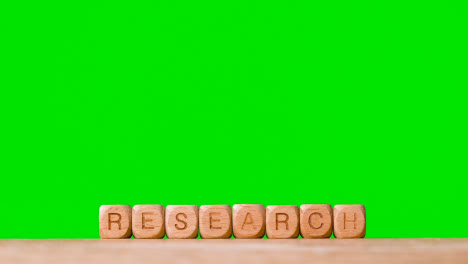 Education-Concept-Shot-With-Wooden-Letter-Cubes-Or-Dice-Spelling-Research-Against-Green-Screen