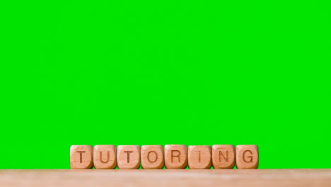 Education-Concept-With-Wooden-Letter-Cubes-Or-Dice-Spelling-Tutoring-Against-Green-Screen