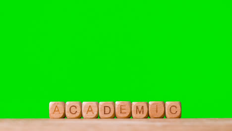 Bildungskonzept-Mit-Holzbuchstabenwürfeln-Oder-Würfeln,-Die-Akademisch-Gegen-Grünen-Bildschirm-Buchstabieren