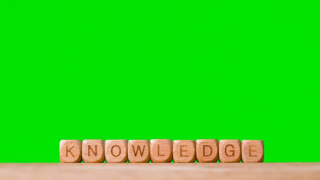 Education-Concept-Shot-With-Wooden-Letter-Cubes-Or-Dice-Spelling-Knowledge-Against-Green-Screen
