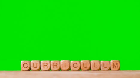 Education-Concept-With-Wooden-Letter-Cubes-Or-Dice-Spelling-Curriculum-Against-Green-Screen-Background