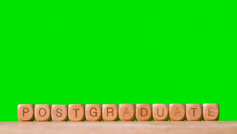 Bildungskonzept-Mit-Holzbuchstabenwürfeln-Oder-Würfeln,-Die-Postgraduale-Auf-Grünem-Bildschirm-Buchstabieren