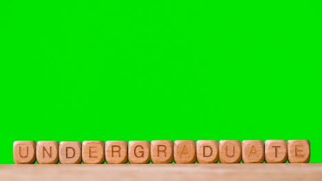 Education-Concept-With-Wooden-Letter-Cubes-Or-Dice-Spelling-Undergraduate-Against-Green-Screen