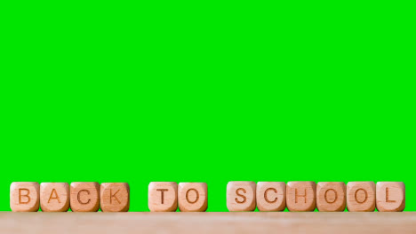 Education-Concept-With-Wooden-Letter-Cubes-Or-Dice-Spelling-Back-To-School-Against-Green-Screen-Background