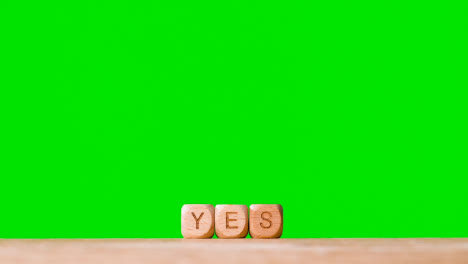 Concept-With-Wooden-Letter-Cubes-Or-Dice-Spelling-Yes-Against-Green-Screen-Background