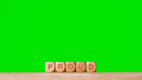 Concept-With-Wooden-Letter-Cubes-Or-Dice-Spelling-Proud-Against-Green-Screen-Background