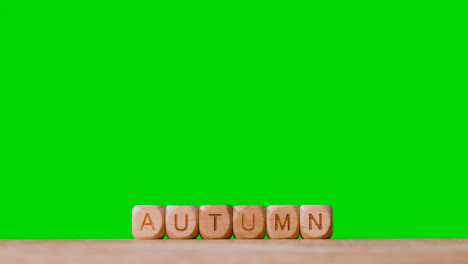 Konzept-Mit-Hölzernen-Buchstabenwürfeln-Oder-Würfeln,-Die-Herbst-Vor-Grünem-Hintergrund-Buchstabieren
