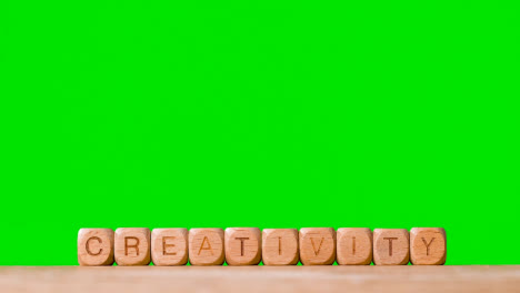 Concept-With-Wooden-Letter-Cubes-Or-Dice-Spelling-Creativity-Against-Green-Screen
