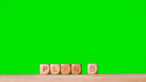 Concept-With-Wooden-Letter-Cubes-Or-Dice-Spelling-Plan-B-Against-Green-Screen