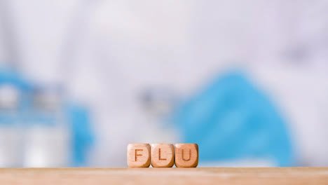 Medical-Concept-With-Wooden-Letter-Cubes-Or-Dice-Spelling-Flu-Against-Background-Of-Scientist-Working-In-Laboratory