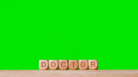 Medical-Concept-With-Wooden-Letter-Cubes-Or-Dice-Spelling-Doctor-Against-Green-Screen-Background