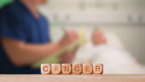 Medical-Concept-With-Wooden-Letter-Cubes-Or-Dice-Spelling-Cancer-Against-Background-Of-Nurse-Talking-To-Patient-In-Hospital-Bed