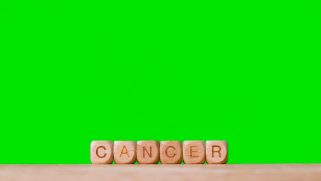 Medizinisches-Konzept-Mit-Holzbuchstabenwürfeln-Oder-Würfeln,-Die-Krebs-Vor-Grünem-Hintergrund-Buchstabieren