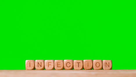 Medical-Concept-With-Wooden-Letter-Cubes-Or-Dice-Spelling-Infection-Against-Green-Screen-Background