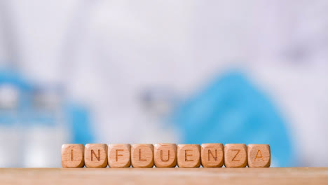 Medical-Concept-With-Wooden-Letter-Cubes-Or-Dice-Spelling-Flu-Against-Background-Of-Scientist-Working-In-Laboratory