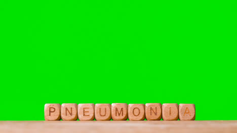 Medical-Concept-With-Wooden-Letter-Cubes-Or-Dice-Spelling-Pneumonia-Against-Green-Screen-Background