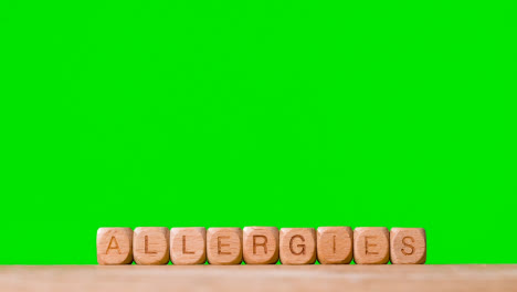 Medizinisches-Konzept-Mit-Holzbuchstabenwürfeln-Oder-Würfelallergien-Vor-Grünem-Hintergrund