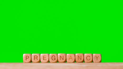 Konzept-Mit-Hölzernen-Buchstabenwürfeln-Oder-Würfeln,-Die-Schwangerschaft-Vor-Grünem-Hintergrund-Buchstabieren