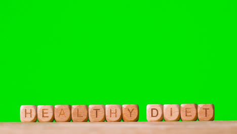 Medical-Concept-With-Wooden-Letter-Cubes-Or-Dice-Spelling-Healthy-Diet-Against-Green-Screen-Background