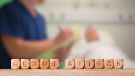 Concepto-Médico-Con-Cubos-De-Letras-De-Madera-O-Dados-Que-Deletrean-Ataque-Cardíaco-Contra-El-Fondo-De-La-Enfermera-Hablando-Con-El-Paciente-En-La-Cama-Del-Hospital