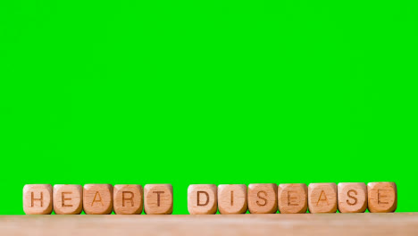 Medical-Concept-With-Wooden-Letter-Cubes-Or-Dice-Spelling-Heart-Disease-Against-Green-Screen