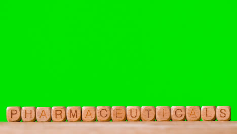 Medical-Concept-With-Wooden-Letter-Cubes-Or-Dice-Spelling-Pharmaceuticals-Against-Green-Screen-Background