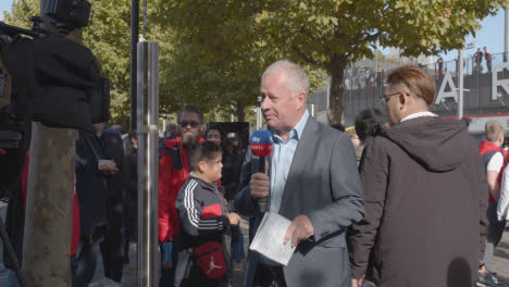 TV-Sportreporter-Außerhalb-Des-Emirates-Stadium-Home-Ground-Arsenal-Football-Club-London-Mit-Fans-Am-Spieltag